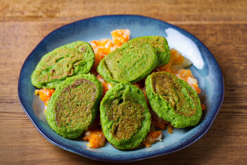 Green pea cakes on mashed carrot and parsnip. Vegetable fritters, pancakes on blue plate
