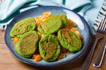 Green pea cakes on mashed carrot and parsnip. Vegetable fritters, pancakes on blue plate