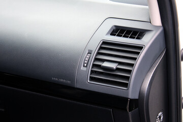 Obraz premium Car air conditioning. The air flow inside the car. Car ventilation close-up. Elements of a car air conditioning. Details of the front panel of SUV with air diffusers. Passenger airbag. Front airbag.