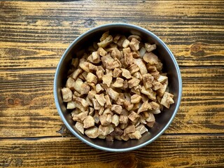 A bowl of fried pork cracklings on a rustic wooden table. Traditional homemade food.