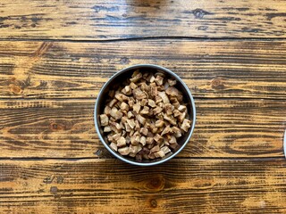 A bowl of fried pork cracklings on a rustic wooden table. Traditional homemade food.