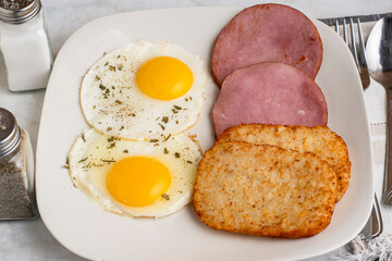 fried eggs with sliced ham and hash browns