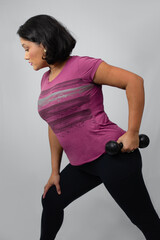 Empowered woman performing weight lifting with dumbbell at studio. Perfect for triceps workout, fitness, strength training. Neutral gray background with copy space.