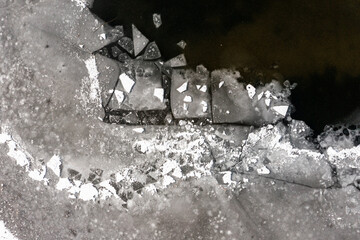 The texture of a frozen lake and pieces of floating ice in the water. Winter landscape from a drone.
