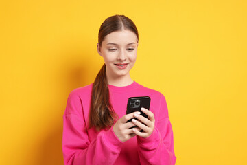 Fototapeta premium Teenage girl with smartphone on yellow background