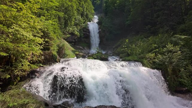 Multi-tiered Giessbach Waterfalls cascade through dense green forest near Lake Brienz, Switzerland. 4K UHD video.