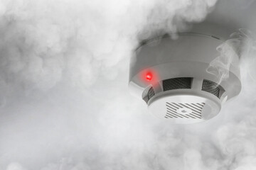 Fire alarm system detector on ceiling triggered by smoke