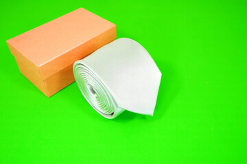 A plain tie rolled with gift box closeup shot on green background 