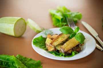 Zucchini with a crispy crust and fresh salad on a brown background
