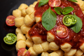Close up on traditional italian potato gnocchi in tomato sauce with fresh basil and Cherry tomato