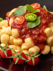 Close up on traditional italian potato gnocchi in tomato sauce with fresh basil and Cherry tomato