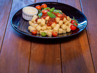 Close up on traditional italian potato gnocchi in tomato sauce with fresh basil and Cherry tomato