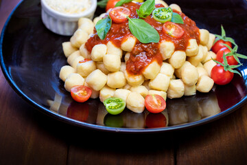Close up on traditional italian potato gnocchi in tomato sauce with fresh basil and Cherry tomato
