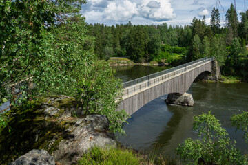 Fototapeta premium A scenic summer view of the historic Old Fossum Bridge spanning the Glomma River in Østfold County, Norway