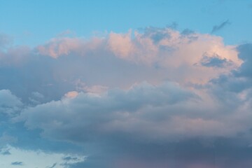 Expansive sky filled with soft pink, orange cumulus or cumulonimbus clouds illuminated by the sun at dawndusk natural scene captured in realistic style without filters