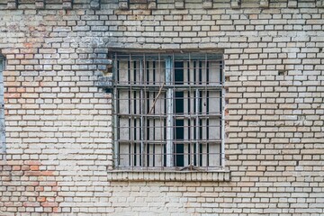 Angled view of a worn, charred brick building with boarded window, taken in natural daylight, depicting signs of decay and neglect