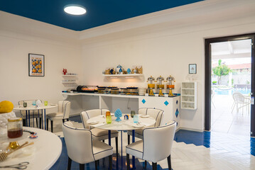 Bright dining room with blue and white decor, marble tables, buffet counter, ceramic ornaments, and...