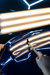 Controlled taps with a knockdown tool reshape metal warped by hail. PDR technician uses a knockdown...