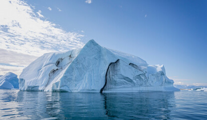 Large  iceberg with deep crevasse and dramatic sky in Disko Bay in Greenland