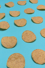 Numerous round nachos carefully arranged on a light blue-green background