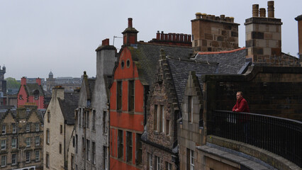 Naklejka premium Man on balcony admiring the beautiful medieval city of Edinburgh, Scotland UK