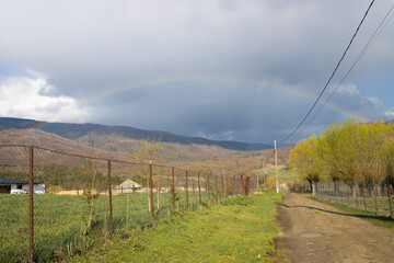 Fading rainbow over a rural landscape. Dirt road in the romanian countryside