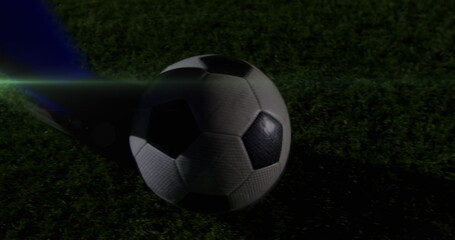 Image of light trails over football player kicking ball at stadium