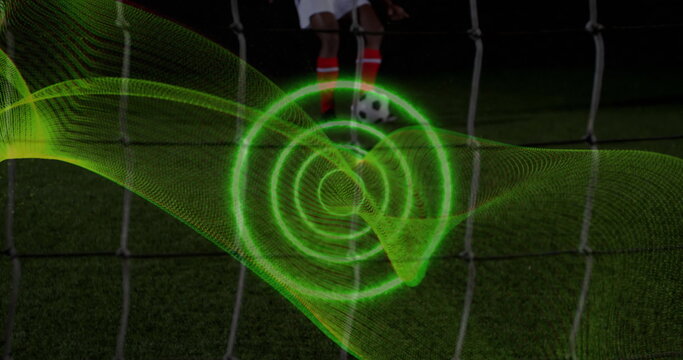 Image of spiral light trail against mid section of male soccer player taking a penalty kick