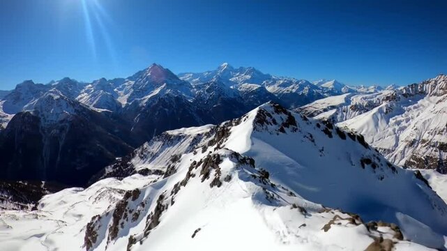 Snow-covered mountains with a clear blue sky, offering a stunning panoramic view. The scene evokes a sense of awe and wonder
