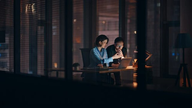Hardworking businesspeople browsing laptop at dark office. Smiling businesswoman - Powered by Adobe