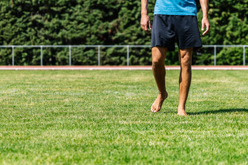 Athlete walking barefoot on grass field after training session