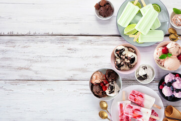 Cool summer food side border. Variety of ice cream bowls, popsicles and frozen treats. Top view on a white wood background. Copy space.