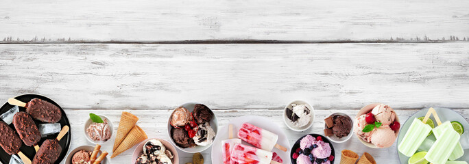 Cool summer food bottom border. Assortment of ice cream bowls, popsicles and frozen treats. Top down view on a white wood banner background. Copy space.