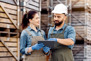 Professionals work in warehouse, check goods with device, collect order. Smiling millennial lady...