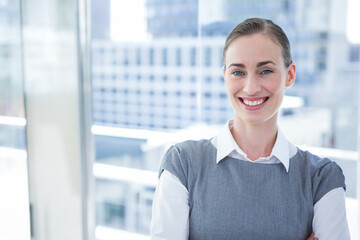 Businesswoman in business attire standing arms crossed on balcony with glass railing, copy space