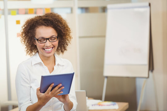 African American woman holding tablet while reviewing sticky notes and flip chart in office