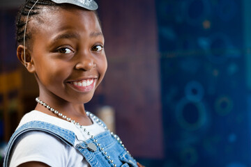 African American girl smiling at studio wearing glitter cowboy hat and beaded necklace, copy space