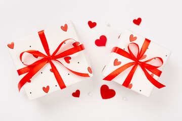 Festive gift boxes with red hearts on color background, top view