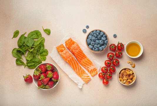 Raw salmon fillets, spinach, strawberries, blueberries, cherry tomatoes, almonds and olive oil. Set of foods that help to reduce inflammation, top view