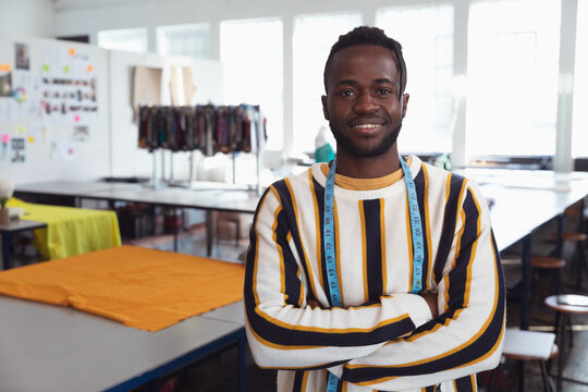 African American man measuring swatches with tape at worktable in well-lit design studio