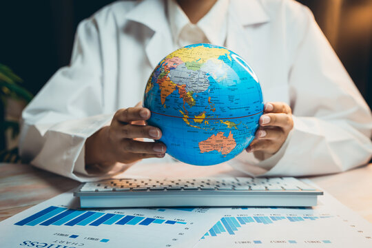 Medical concept. Doctor Holding Globe While Analyzing Data on Computer in Modern Office Setting