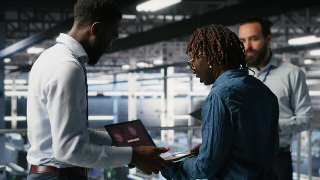 Worried workers trying to fix hacked infrastructure systems. Panicked engineers in data center react to ransomware warning on laptop screen, scrambling to launch emergency response protocol, camera B