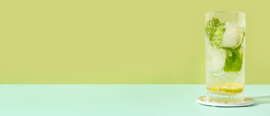 Glass of fresh mojito on blue table against green background