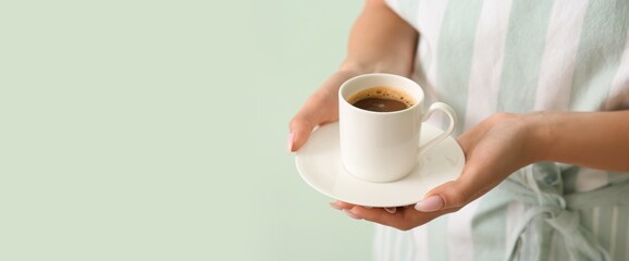 Young woman with cup of hot coffee on mint background, closeup