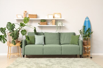 Interior of living room with green sofa, plants and surfboard