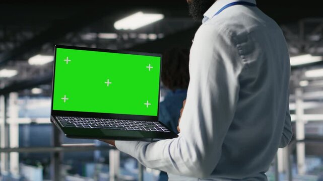 Close up of engineer on data center industrial platform analyzing performance outputs on green screen laptop. Server room IT expert finetuning server rig configurations using mockup notebook, camera B