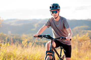 Portrait of a smiling young man wearing a helmet and mirrored sunglasses while holding his mountain...