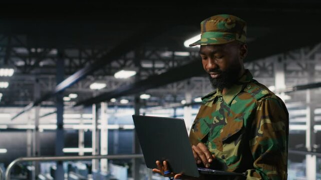 Army technician in command center server room using laptop to install and maintain IT systems. Military data center admin overseeing computer networks and information systems, camera B