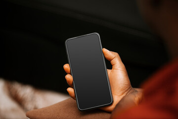 Black African male person Hand sitting holding mobile phone with black blank screen in living room, social media, news, entertainment