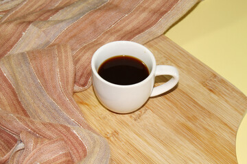 Cup of coffee on the rustic cutting board and fabric.
